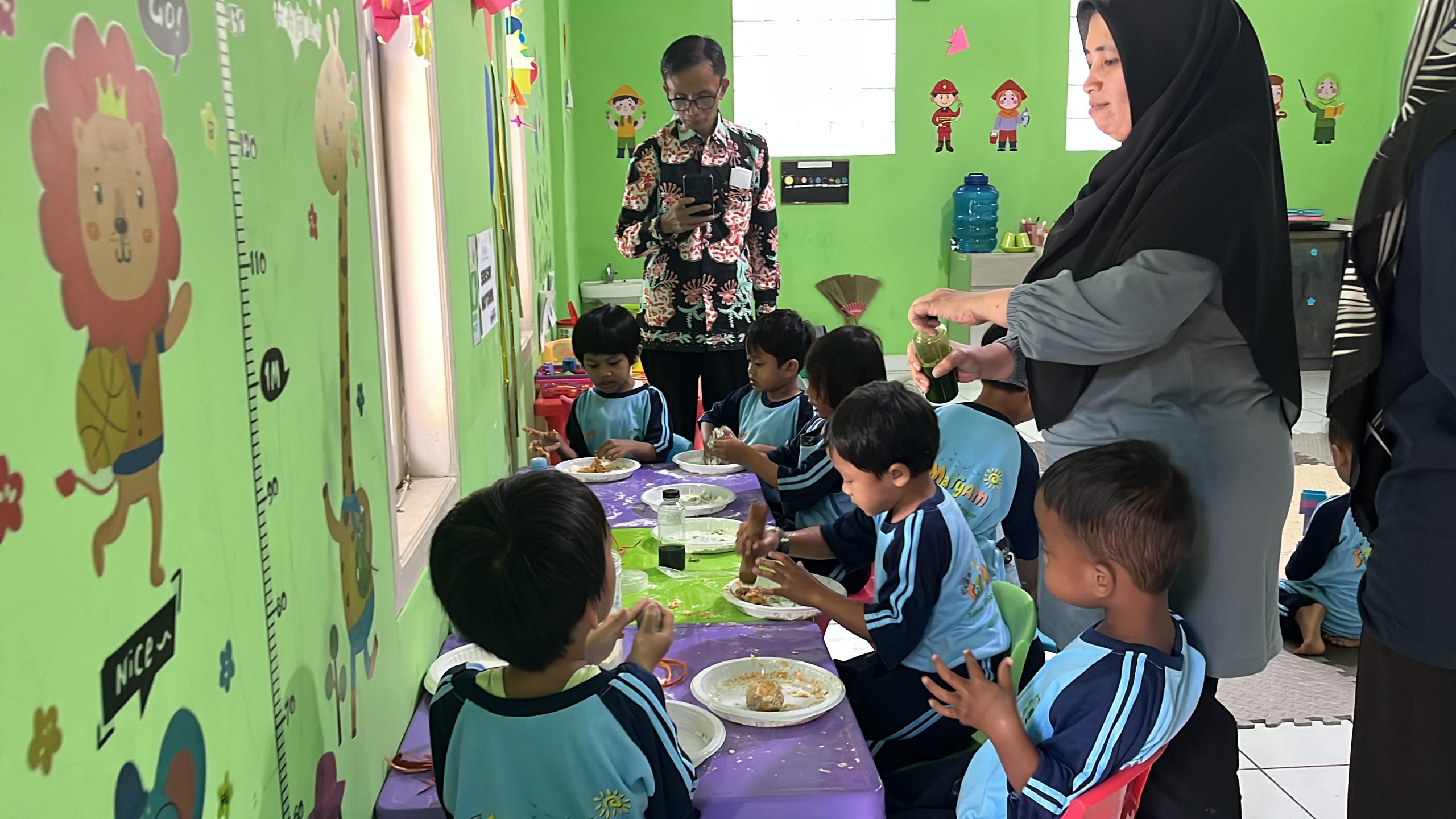 Asesor Supriatna, S.Ag., MPd. mendokumentasikan proses siswa TK A membuat playdough (lilin malam) dari bahan tepung terigu, minyak goreng, dan pewarna alami (daun suji, secang, arang, ampas kopi)